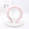 A pink sponge terry cloth headband for hair styling displayed on a white stand.