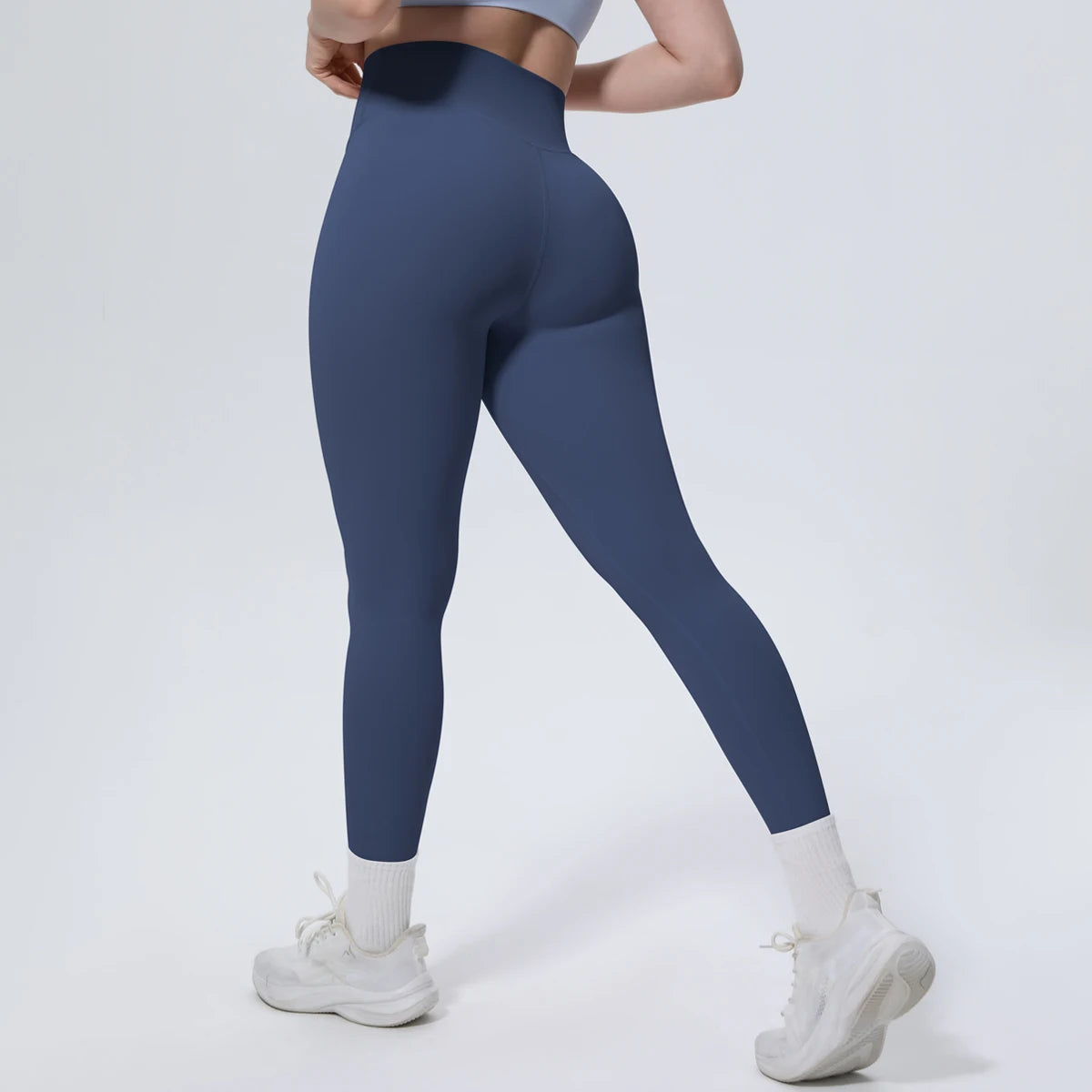 A model wearing dark blue high-waisted quick-drying yoga leggings and white socks, standing in a neutral pose.