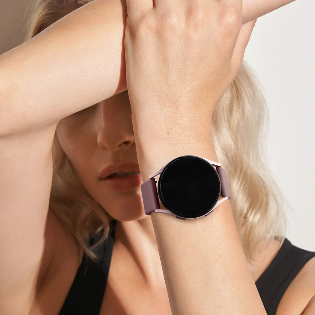 A close-up of a woman wearing a black silicone watch strap on her wrist.