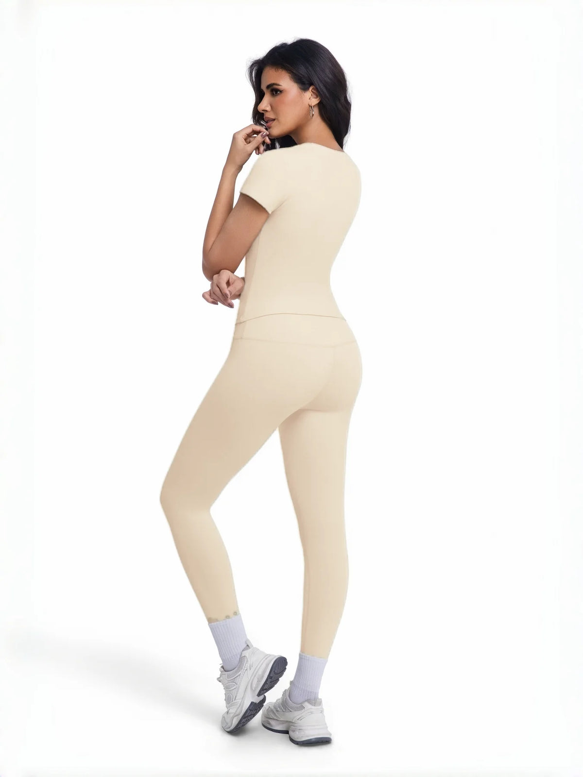 Una mujer modela un conjunto de yoga sin costuras de talle alto en beige, con un top ajustado y leggings.