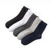 Une pile de chaussettes de coton premium en différentes couleurs : noir, blanc, gris et bleu marine.