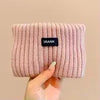 A light pink knitted headband with the brand name 'FRANK' visible on the front.