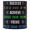A set of five black silicone wristbands with motivational words like Success, Achieve, Focus, and Realize your Potential
