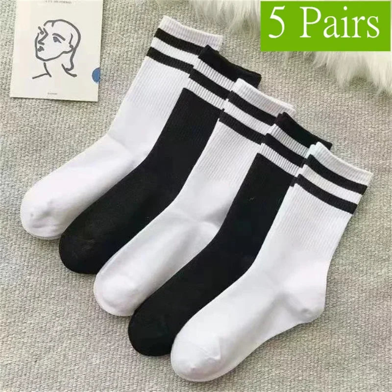 Five pairs of black and white striped casual socks laid out on a light gray fabric.