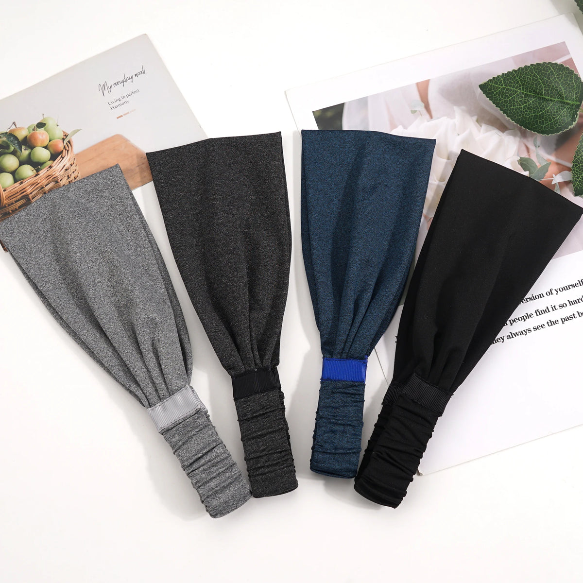 Une collection de quatre bandeaux élastiques sport multi-usages gris, bleu foncé et noir sur un fond blanc