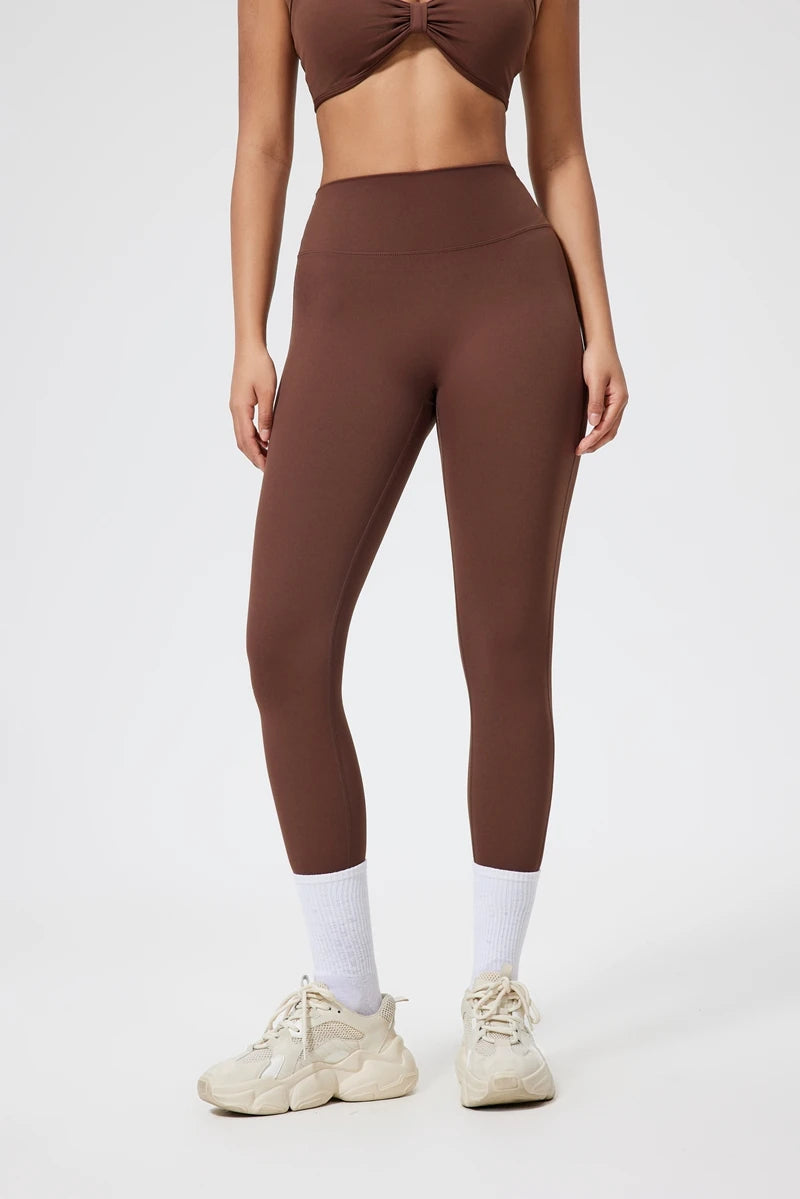 Model wearing seamless high-waist yoga leggings and a matching cropped top in brown.