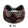 A patterned boho cotton turban headband featuring geometric designs in maroon, black, white, and teal.