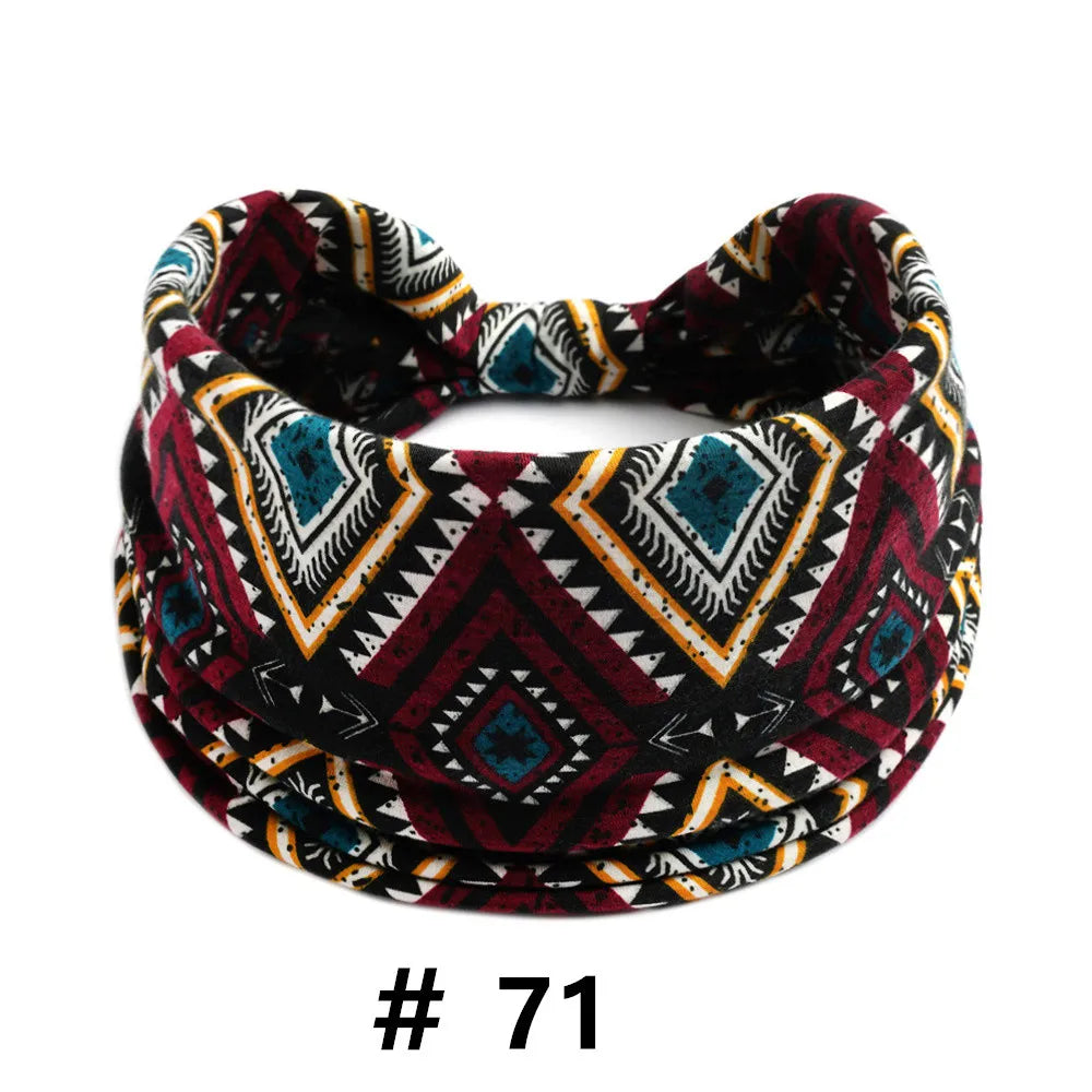 A patterned boho cotton turban headband featuring geometric designs in maroon, black, white, and teal.