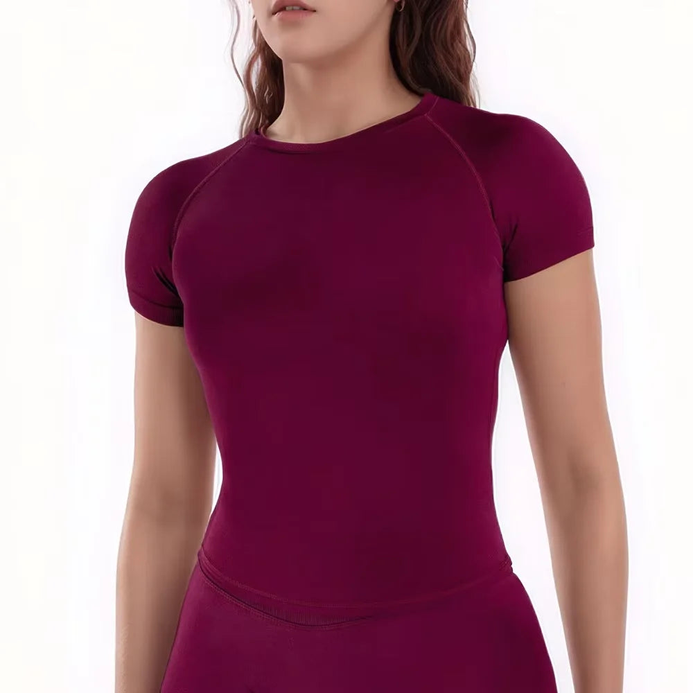 A woman wearing a deep magenta performance fitness short sleeve top.