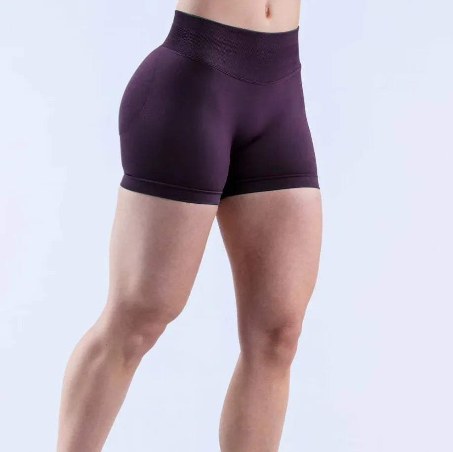 A model is wearing seamless high-waisted yoga shorts in a deep purple color.