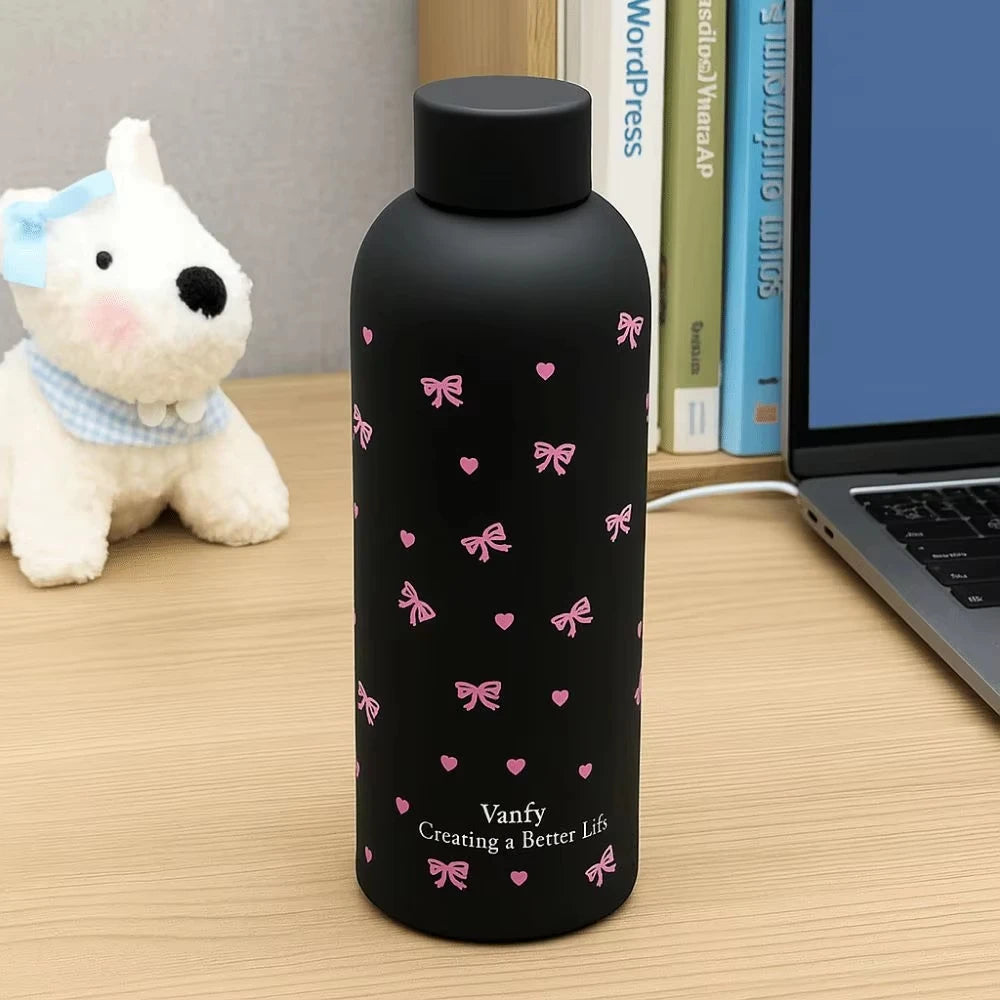 Taza de viaje de acero inoxidable aislada negra con diseños de cinta floral rosa sobre un escritorio de madera junto a una la