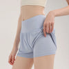 Light blue women's high-waist yoga and fitness shorts being held by a hand.