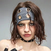 Une femme portant un bandeau en œillet punk grunge gris foncé avec des anneaux argentés dans ses cheveux foncés.