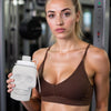 A woman holds a white skull design leakproof foldable sports water bottle in a brown sports bra.