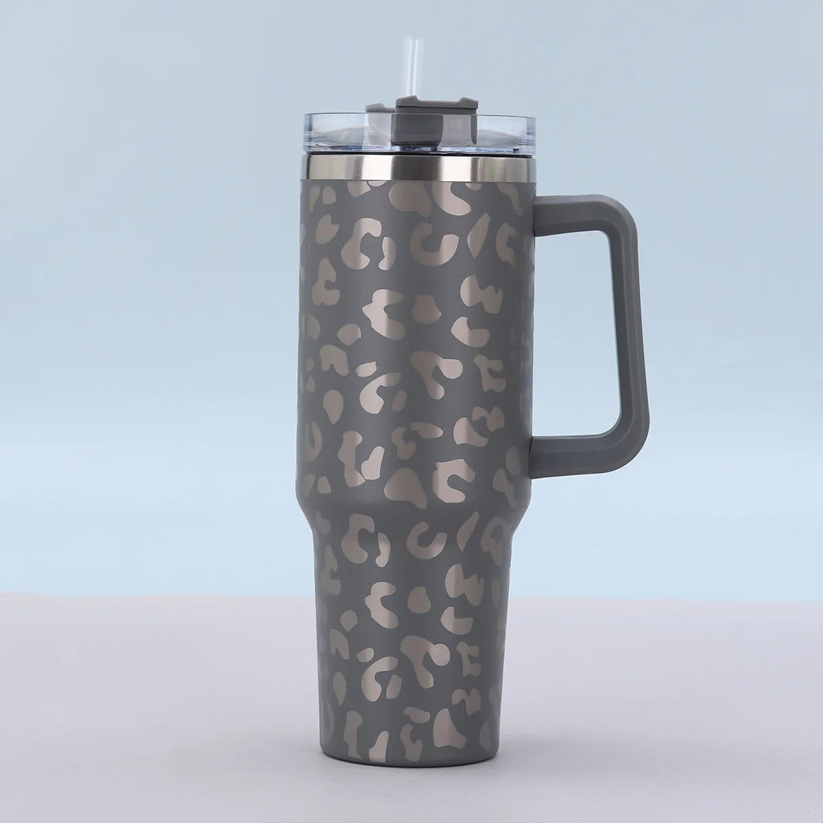 Tasse isotherme en acier inoxydable avec motif léopard et couvercle en paille transparente.
