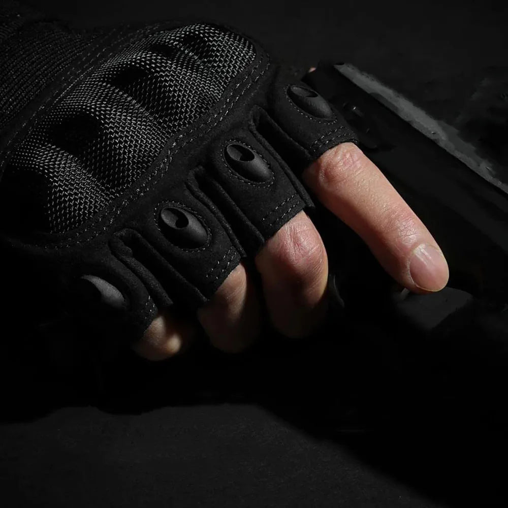 A hand wearing black tactical fingerless gloves gripping a dark object.