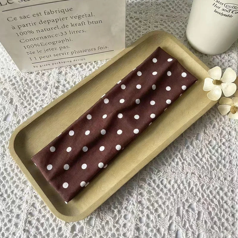 Braunes Polka-Dot-Stoff-Haarband auf Holztablett neben Produktinformationen