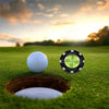 A white golf ball rests on a green grass putting surface next to a black slope meter marker in the sunset light.